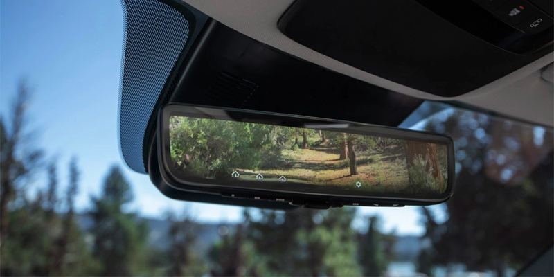 Digital rearview mirror displaying outdoor scenery behind vehicle.