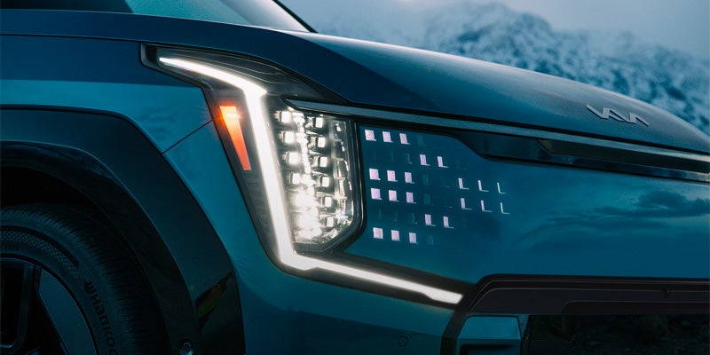 A close-up of the Kia EV9's futuristic front headlight and grille