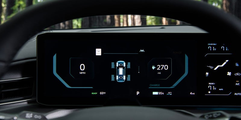 The digital dashboard display of the car, with gauges and a vehicle icon