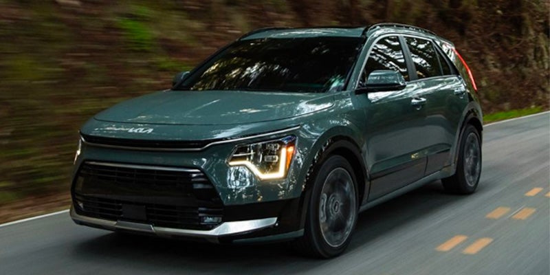 A green Kia Niro EV driving on a winding road with blurred motion