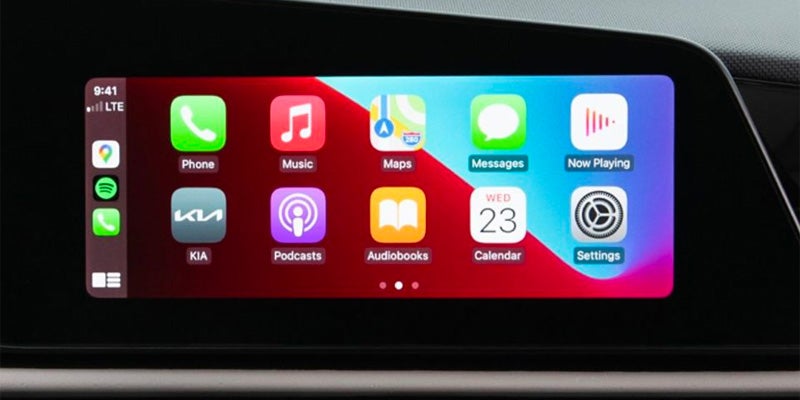 The car's infotainment screen, which is displaying the Apple CarPlay interface with various app icons