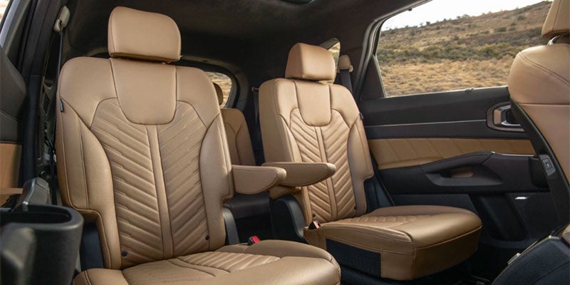 The interior of an SUV with beige leather seats in two rows.