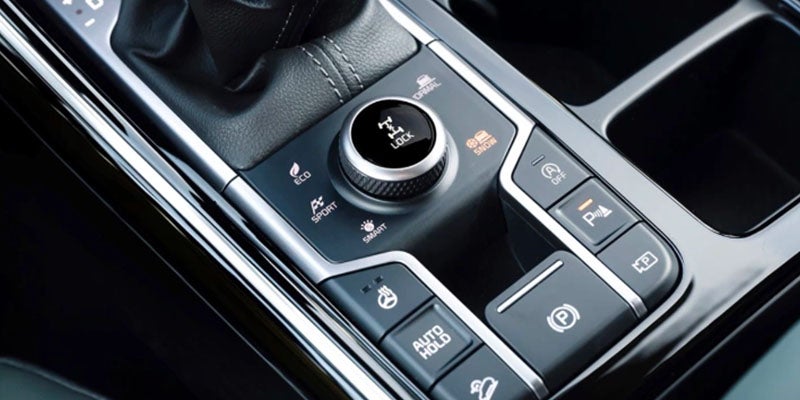 A close-up of a gear shifter and drive mode selector in an SUV