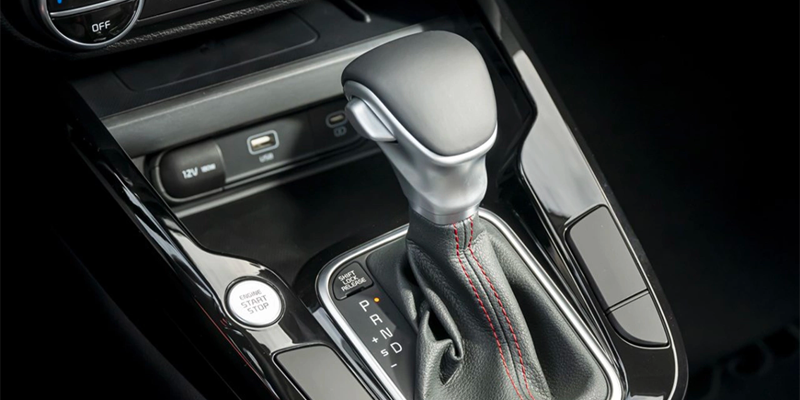 The automatic gear shifter and engine start button of a Kia